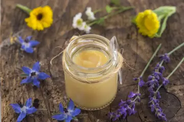 Vasetto di pappa reale, circondato da fiori blu e gialli. Chissà dopo quanto fa effetto questo prezioso nettare.
