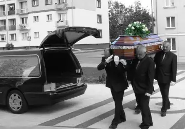 Pogrzebowa karawan i trzej mężczyźni niosący trumnę z kwiatami. Ostatnio odeszli.