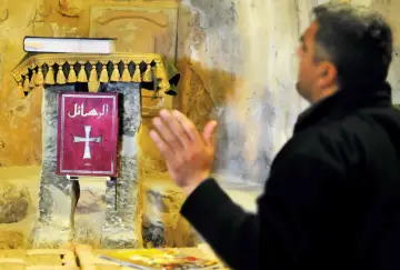 Mężczyzna modli się przed czerwoną księgą z krzyżem. Różnorodność religii w Kazachstanie jest fascynująca.