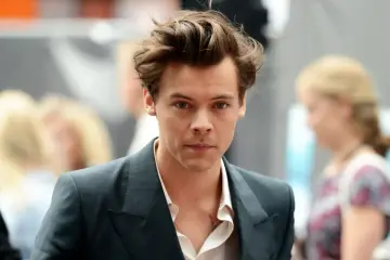 Harry Styles w garniturze, z burzą włosów. Czy Harry Styles jest gejem? Pytanie, które nurtuje fanów.