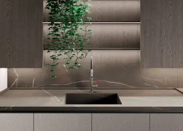 Nowoczesna kuchnia z blatem i płytą backsplash z kamienia, przypominającego marmur. Wisząca zieleń dodaje życia.