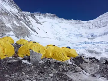 Obóz na wyprawę na Mount Everest. Żółte namioty na kamienistym podłożu, w tle lodowiec i ośnieżone szczyty.