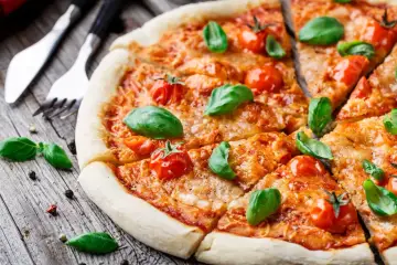Pyszna pizza Margherita z pomidorkami i bazylią, klasyka włoskich dań, gotowa do podania.