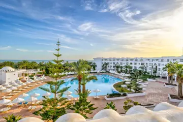 Hotel Palm Azur Djerba: rozległy basen, białe budynki, palmy i morze pod błękitnym niebem. Idealne miejsce na wakacje.