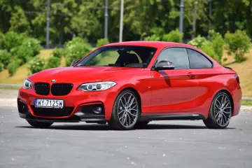 Czerwone BMW f23 coupe z czarnymi dodatkami i felgami stoi na asfalcie.
