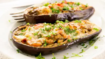 Berenjenas rellenas de carne picada, gratinadas con queso y perejil fresco. Un plato casero y delicioso.