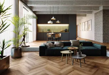 Nowoczesny salon z kuchnią. Drewniana podłoga w jodełkę dodaje elegancji. Sprawdź, jaka jest układanie paneli w jodełkę cena.