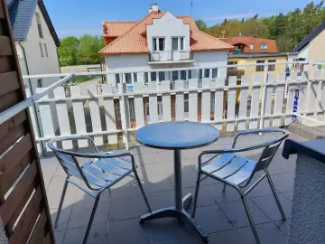 Willa Patryk Jastrzębia Góra: balkon z metalowym stolikiem i dwoma krzesłami, widok na inne budynki i zieleń.