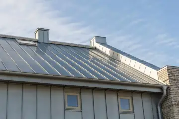 Nowoczesny dach z blachy, pokryty farbą do ocynku, z oknem dachowym i kominem.
