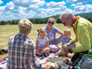 Rodzina na pikniku, ciesząca się słońcem i jedzeniem. Czas na wykorzystanie **bonów turystycznych do kiedy**!