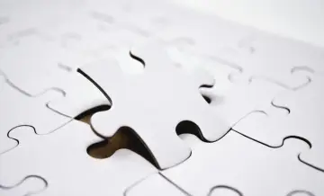 Biała, pojedyncza kostka puzzli leży na tle innych, tworząc paradoks co to znaczy, gdy brakuje jednego elementu?