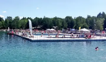Tłum ludzi odpoczywa i kąpie się na pływającym basenie, prawdziwy polski Balaton w słoneczny dzień.