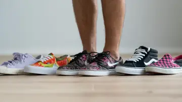 Un hombre elige entre varias zapatillas de **material canvas**. Hay modelos de colores, estampados florales, de cuadros y lisos.