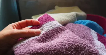 Dłoń dotyka miękkiego ręcznika. Zastanawiasz się, dlaczego płyn do płukania tkanin pogarsza wchłanianie wody przez ręczniki?