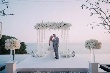 Para młoda pozuje pod kwiecistym baldachimem. Piękna sceneria na zapowiedzi przedślubne z widokiem na ocean.