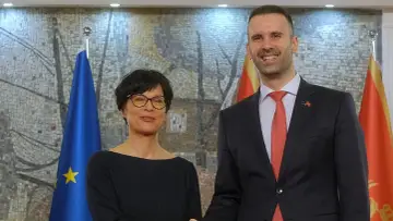 Kobieta i mężczyzna stoją obok flagi UE i Czarnogóry. Czy Czarnogóra jest w Unii? To pytanie nabiera znaczenia w kontekście ich spotkania.