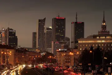 Wieczorny widok na centrum Warszawy, z nowoczesnymi wieżowcami i ruchliwą ulicą, ukazujący położenie geograficzne Warszawy.