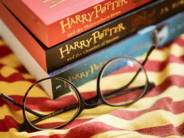 Okulary leżą na tle książek z serii Harry Potter, gotowe do kolejnej magicznej lektury.