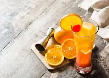 Kolorowy drink z pomarańczy i wiśni, obok pomarańcze i miarka barmańska. Czy sól na rancie szklanki faktycznie wzmacnia smak tequili?