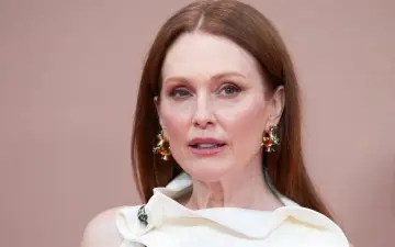 Julianne Moore, znana aktorka, w białej kreacji i efektownych złotych kolczykach.