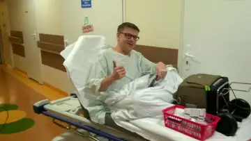 Pacjent po przeszczepie płuc, uśmiechnięty, daje kciuk w górę z łóżka szpitalnego.