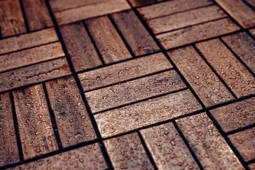 Drewniana, tania podłoga na balkonie po deszczu. Krople wody lśnią na deskach.
