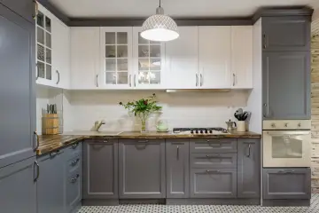 Ett modernt kök med grå och vita skåp. Luckorna är stilrent utformade, redo att måla om för en ny look.