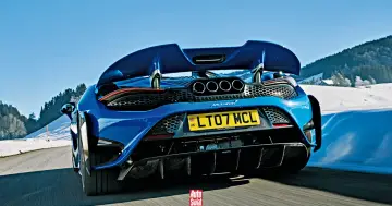 Niebieski McLaren 765LT z czterema końcówkami wydechu pędzi po ośnieżonej drodze w górach.