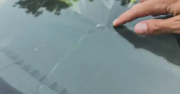 Palec wskazujący na pękniętej szybie samochodowej. Sprawdź autoglass cennik, aby poznać koszt naprawy.