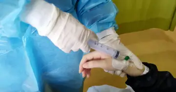 Rękawiczki medyczne przygotowują zastrzyk tocilizumabu.