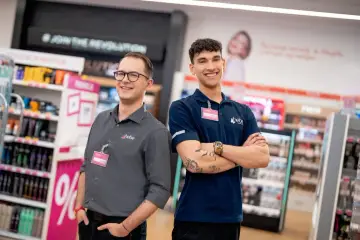 Dwóch uśmiechniętych pracowników Hebe, Alan i Damian, w sklepie. Ciekawe, ile zarabia kierownik Hebe, gdy pracuje się w tak miłej atmosferze.