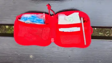 Czerwona saszetka edc z plastrami, rękawiczkami i pęsetą, gotowa na każdą sytuację.