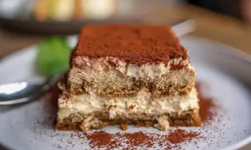 Pyszne tiramisu z warstwami kremu i biszkoptów do tiramisu, posypane kakao.