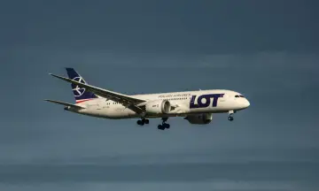 Samolot LOT Polish Airlines z bagażem podręcznym w locie, zbliżający się do lądowania.
