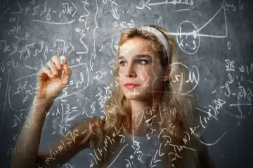 Młoda kobieta z kredą w ręku pisze równania na tablicy. To analogia do procesu uczenia się i odkrywania.