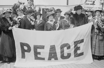 Kobiety z transparentem "PEACE" symbolizują emancypację kobiet i pozytywizm, dążąc do pokoju i równości.