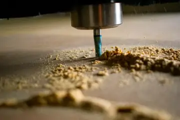 Frezarka CNC obrabia drewno, tworząc wióry. Optymalne parametry skrawania zapewniają precyzję i gładkość powierzchni.