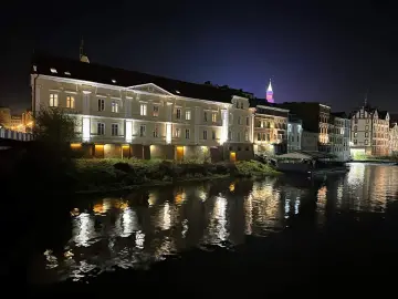 Nocna panorama miasta nad rzeką, z oświetlonymi kamienicami i odbiciami świateł w wodzie. To prawdziwa opolska wenecja.