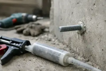 Kotwa chemiczna w betonie, obok pistoletu do jej aplikacji. Czekamy aż kotwa chemiczna schnie.