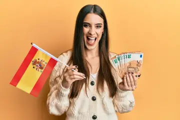 Szczęśliwa kobieta z flagą Hiszpanii i banknotami 50 euro. Marzy o pracy w Hiszpanii i dobrych zarobkach.