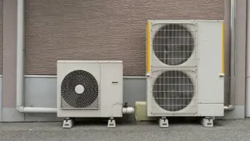 Dwa agregaty czynnika klimatyzacji stoją obok siebie na zewnątrz budynku.