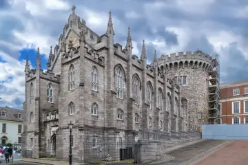 Kamienne mury i strzeliste wieże zdobią zamek w Dublinie. Gotycka architektura i chmurne niebo tworzą majestatyczny widok.