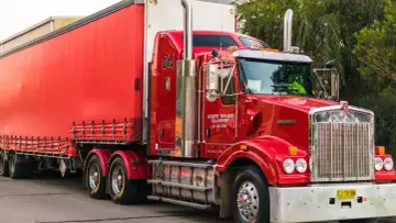 Czerwony, potężny pojazd nienormatywny Kenworth z naczepą, gotowy do transportu.