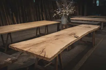Råa ekbord med naturliga kanter, oljade och redo för utomhusbruk. En bukett blommor i en zinkhink står på ett av borden.