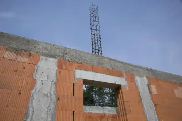 Budowa domu w toku: wieniec ściany szczytowej z pustaków ceramicznych, betonowy nadproże okna i zbrojenie słupa.