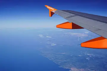 Widok z okna samolotu easyJet na wybrzeże i góry. Bagaż podręczny zmieści się idealnie.