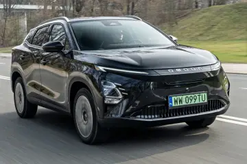 Czarny OMODA elektryk w ruchu drogowym. Nowoczesny design z charakterystycznym pasem świateł LED i logo marki.