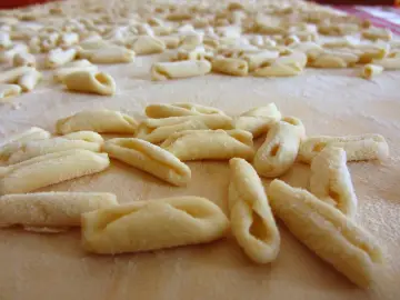 Świeży, swojski makaron przepis na domowe gnocchi. Wiele małych, zakręconych kluseczek ułożonych na blacie posypanym mąką.
