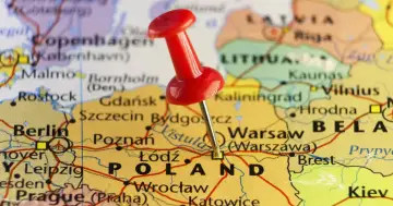 Czerwony pinezka wbita w mapę Polski, zaznaczając Warszawę. Ciekawe miejsca i ciekawostki o Polsce czekają na odkrycie!