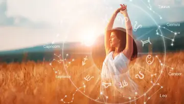 Kobieta w białej sukience cieszy się słońcem na tle złotego pola. Wokół niej krąg znaków zodiaku, zapowiadający horoskop na 2026 panna.